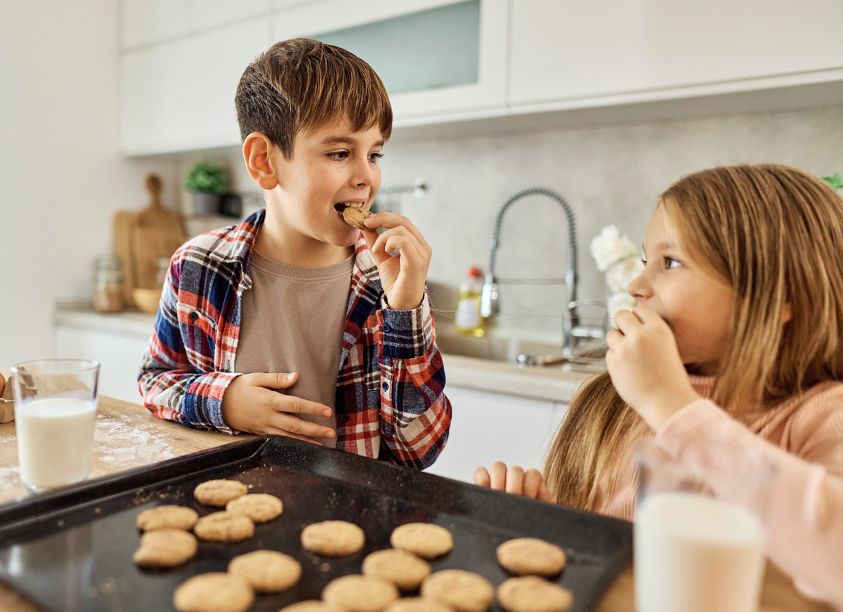 Portret of brother and sister having fun together eating breakfast in kitchen