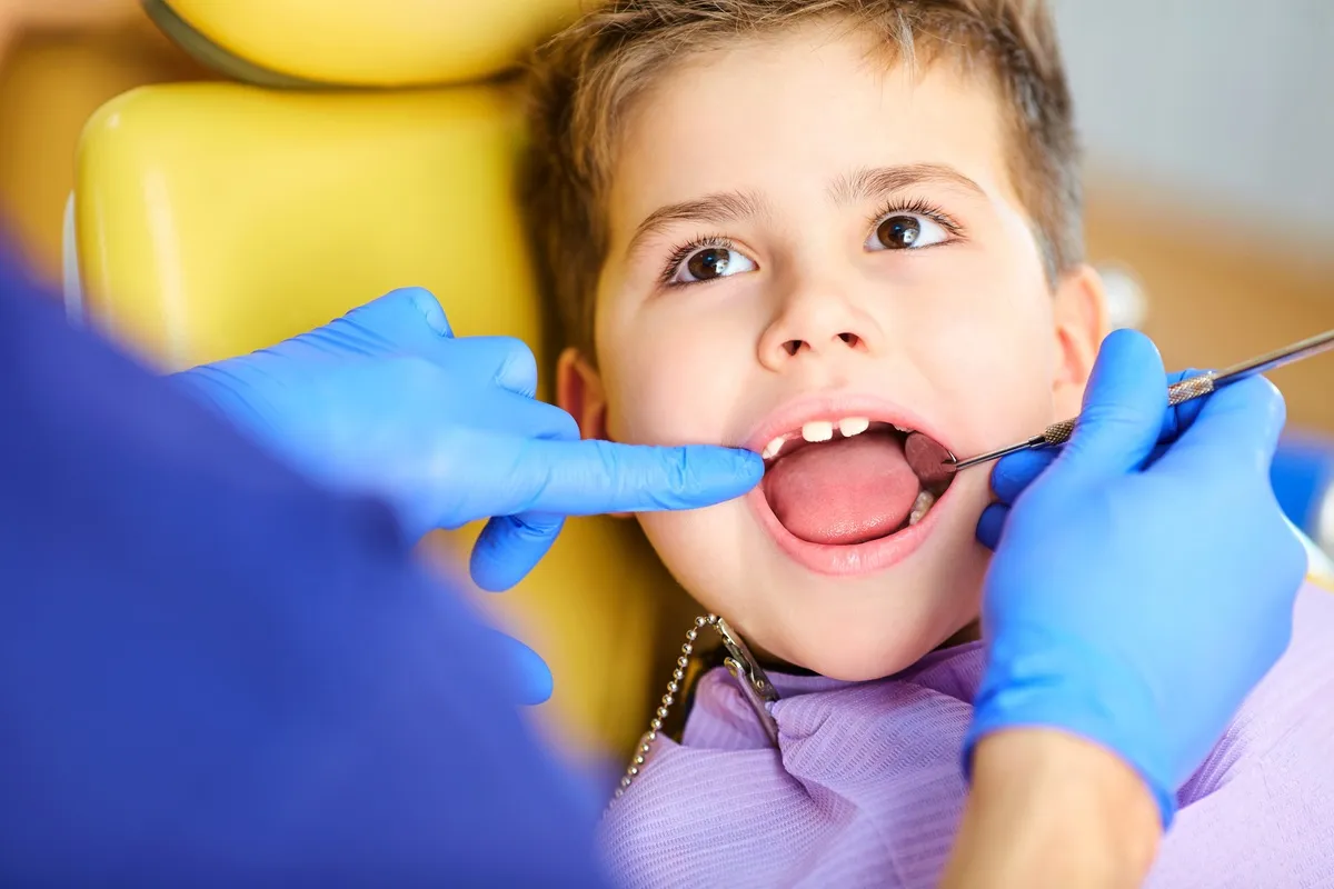 The dentist checking the teeth of boy teenager.