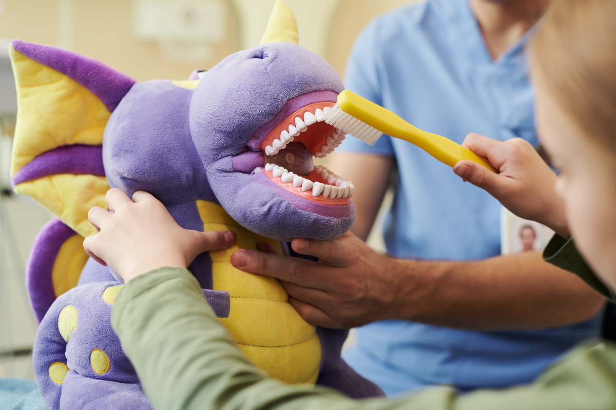 Child Brushing Teeth of Plush Dragon Toy during Dental Hygiene Demonstration