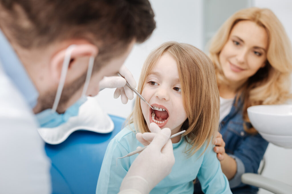 Like an adult. Nice good tempered patient child paying a regular visit to her doctor and sitting still with her mouth open while he examining her teeth