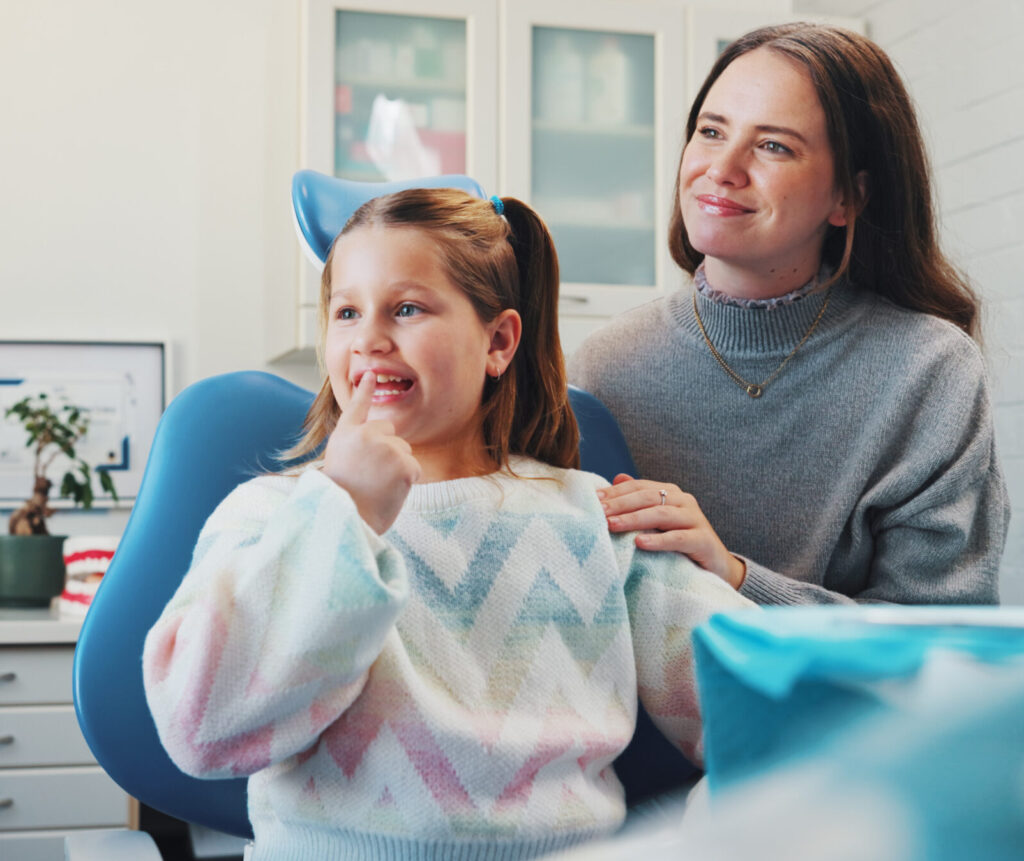 Child, dentist and show tooth at dental consultation with orthodontist for advice or cleaning. Happy girl, family or woman in clinic for gum care, wellness and learning about oral hygiene and health.