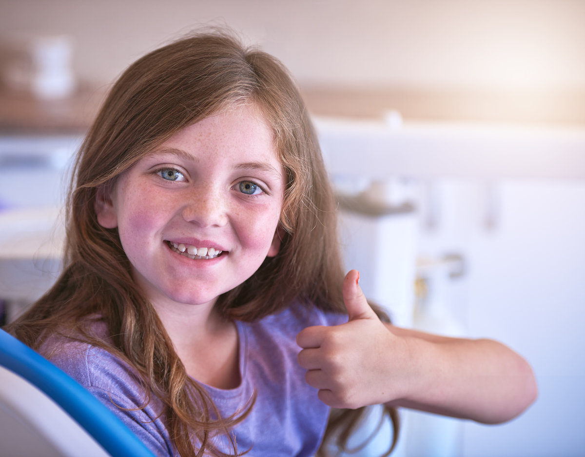 Dentist, child or portrait with thumbs up for teeth cleaning or cavity treatment for oral hygiene or health. Yes sign, good gesture or happy girl with dental filling results, smile or clinic review.