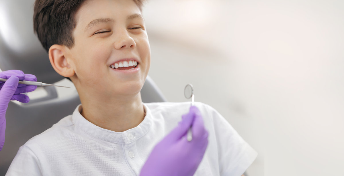 Doctor with gloves examines teeth of happy child boy. Dentist tooth treatment medical procedure, Dental clinic concept.