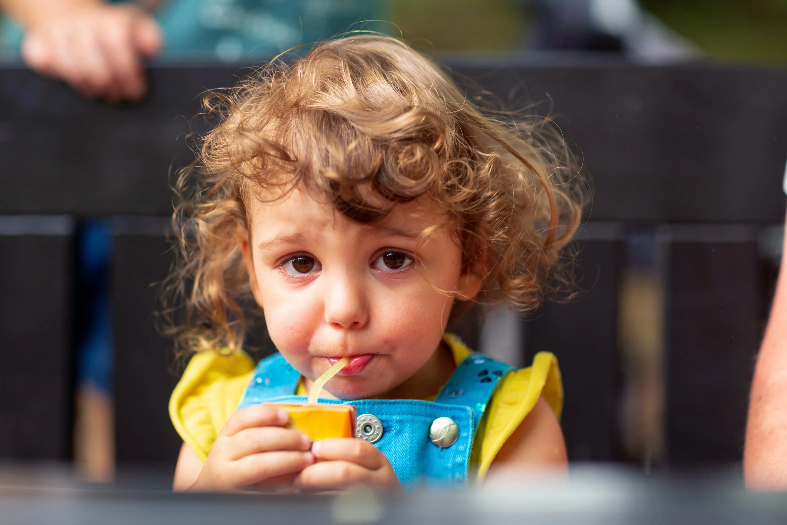 Cute girl drinking juice in park.
