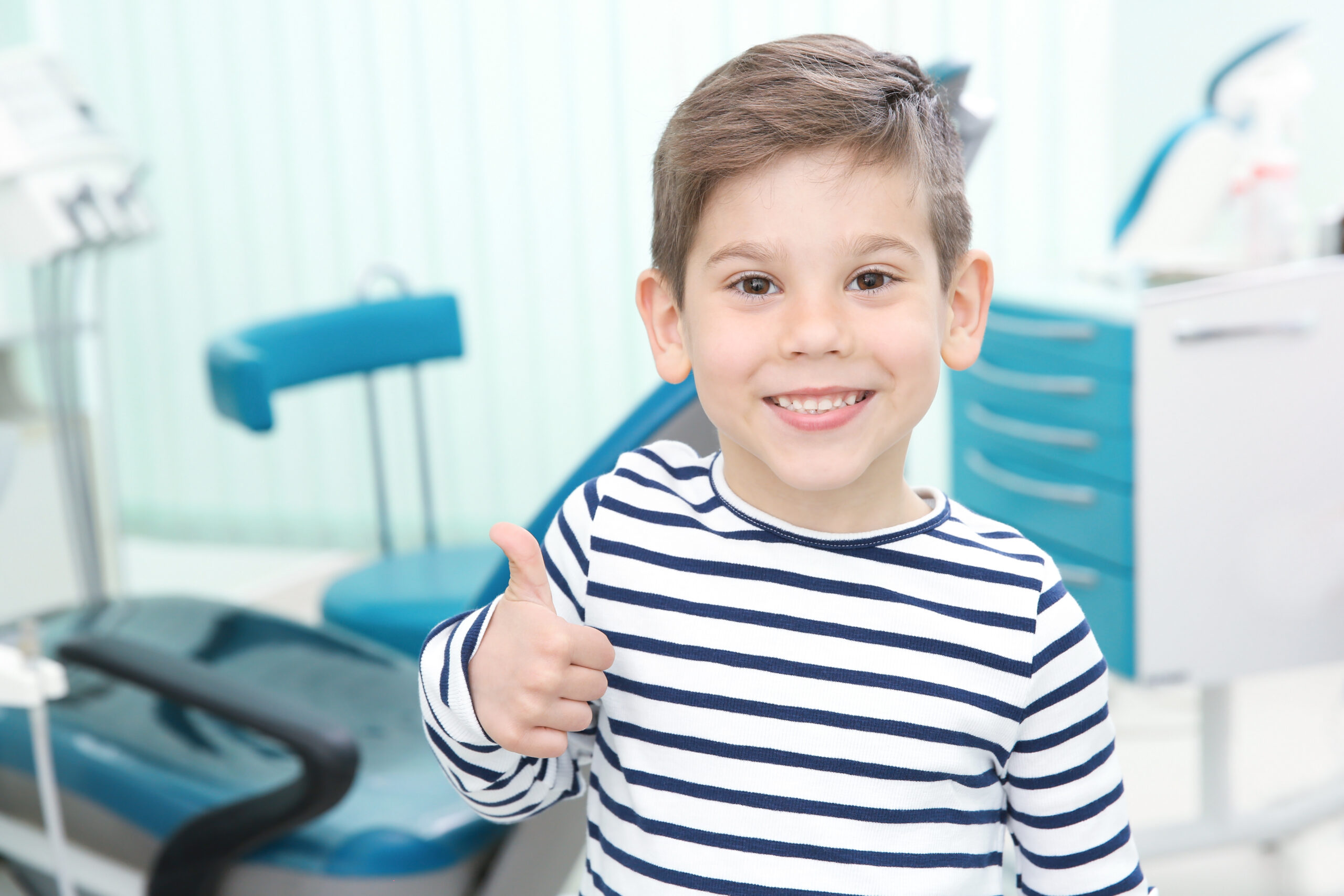 Young boy giving a thumbs up at the pediatric dentist's office