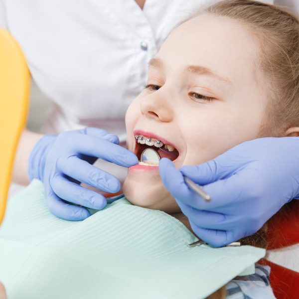 Girl at reception with dentist, conduct an examination of braces and state of enamel from caries.